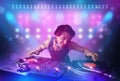 Disc jockey mixing music on turntables on stage with lights and