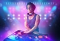 Disc jockey mixing music on turntables on stage with lights and