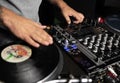Disc jockey scratches vinyl record on turntable player device in night club Royalty Free Stock Photo