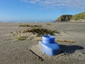 Discarded blue plastic bottle part buried on a beach on New Zealand`s west coast