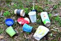 Discarded coffee cups and fast food packaging in the forest on ground. People left behind trash.