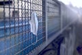 Discarded face mask hanging on a fence.