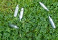 Discarded laughing gas canisters in the grass: metal vials containing nitrous oxide gas, used for whipping cream, but also as a le