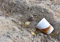Discarded Paper coffee cup on ground. Disposable coffee cup on sand. The problem of environmental pollution. Pile of abandoned