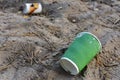 Discarded Paper coffee cup on ground. Disposable coffee cup on sand. The problem of environmental pollution. Pile of abandoned