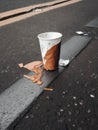 A discarded paper cup torn and stained lying in the street.. AI generation