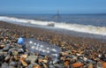 Discarded plastic bottle washed up on pebble beach Royalty Free Stock Photo