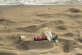 Discarded trash pollution on sandy sea shore,plastic glass,coke can packaging
