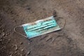 Discarded used disposable face mask lying on ground in puddle