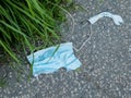 Discarded used, torn and dirty face mask on the concrete floor