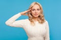 Disciplined and responsible blond woman in knitted sweater holding hand near head saluting, patriotic gesture, honor and dignity