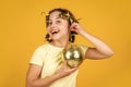 disco ball decoration. lovely girl with disco ball. Fashion girl posing in curlers on yellow wall. saturday night and Royalty Free Stock Photo