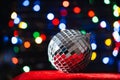 disco ball on red velvet podium on multicolor fairy string light bokeh Royalty Free Stock Photo