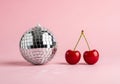 A disco ball and two cherries on a pink background Royalty Free Stock Photo