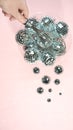 Disco balls for decoration party shattering into small balls in a bowl with whisk in hand on pastel pink gradient background. Royalty Free Stock Photo