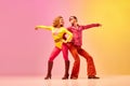 Disco dance. Stylish expressive excited couple of professional dancers in retro style clothes dancing over pink-yellow