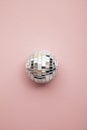 Disco glitter mirror ball on a pastel pink background