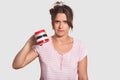 Discontent upset woman in pyjamas keeps mug down, demonstrates that she has no coffee to drink, needs to go in shop, stands agains