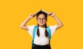 Discontented Asian Schoolgirl Posing With Book On Head In Studio