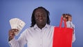 Discount concept. African american black man holding money and shopping bag in his hands. Saving money during the sale Royalty Free Stock Photo