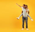 Discounts for family and kids. Excited black man giving piggyback ride for daughter, cute girl pointing at empty space Royalty Free Stock Photo