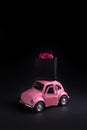 Discounts shopping, sale concept on black friday, cyber monday, pink toy car carrying a paper shopping bag on the roof on a black Royalty Free Stock Photo