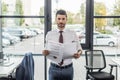 discouraged businessman looking at camera while holding documents.