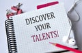 DISCOVER YOUR TALENTS! - words in a white notebook on a white background with headphones and a pencil