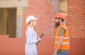 Discuss progress plan. Construction industry concept. Woman engineer and bearded brutal builder discuss construction Royalty Free Stock Photo