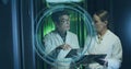 Discussing engineers in labcoats sharing data in data center aisle, with tablet and digital overlay Royalty Free Stock Photo