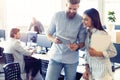 Discussing new business project. Two happy young people in casual wear smiling and looking at digital tablet while Royalty Free Stock Photo