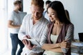 Discussing new business project. Two happy young people smiling and looking at digital tablet while working together Royalty Free Stock Photo