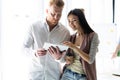 Discussing new business project. Two happy young people smiling and looking at digital tablet while working together Royalty Free Stock Photo