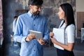 Discussing new business project. Two happy young people in casual wear smiling and looking at digital tablet while Royalty Free Stock Photo