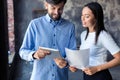 Discussing new business project. Two happy young people in casual wear smiling and looking at digital tablet while Royalty Free Stock Photo