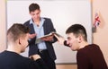 Discussion in the lesson. Youn teacher with book in background. Royalty Free Stock Photo