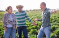 Farmer reprimanding male and female workers in farm field