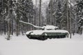 disguised tank under the snow rides among the trees in the forest.