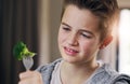 Disgust, food and dislike with child and broccoli for nutrition, health and cooking. Sad, angry and dinner with boy and Royalty Free Stock Photo