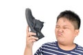 Disgusted boy holding a pair of smelly leather shoes