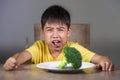 Disgusted child refusing to eat healthy green broccoli feeling upset in kid nutrition education on healthy fresh food and young