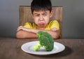 Disgusted child refusing to eat healthy green broccoli feeling upset in kid nutrition education on healthy fresh food and young Royalty Free Stock Photo