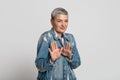 Disgusted middle-aged woman feeling aversion about something, standing over light background