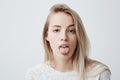 Disgusted pretty young woman with blonde hair sticking out tongue, expressing her dislike or disregard towards something Royalty Free Stock Photo