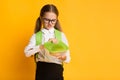 Disgusted Schoolgirl Looking At Sandwich In Lunchbox, Yellow Background