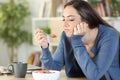 Disgusted woman eating breakfast cereal bowl at home