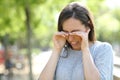 Disgusted woman rubbing her eyes in a park