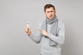 Disgusted young man in gray sweater, scarf pointing index finger on daily pill box isolated on grey background. Healthy