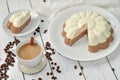 A dish with an appetizing mousse layer (vanilla and chocolate) cake and a cup of milk coffee on a wooden surface