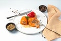 Dish with bell pepper with meat and rice in a white plate with spices, Cutlery and napkin on a light background. Royalty Free Stock Photo